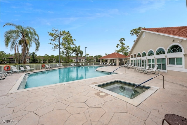 community pool with a patio area, a community hot tub, and fence