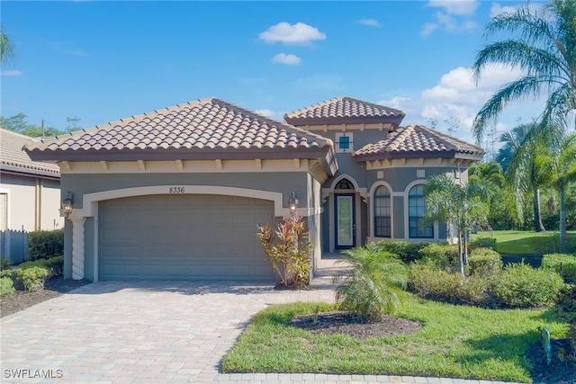 8336 Adelio Ln, Fort Myers, FL 33912 - mediterranean / spanish house with stucco siding, an attached garage, decorative driveway, and a tiled roof