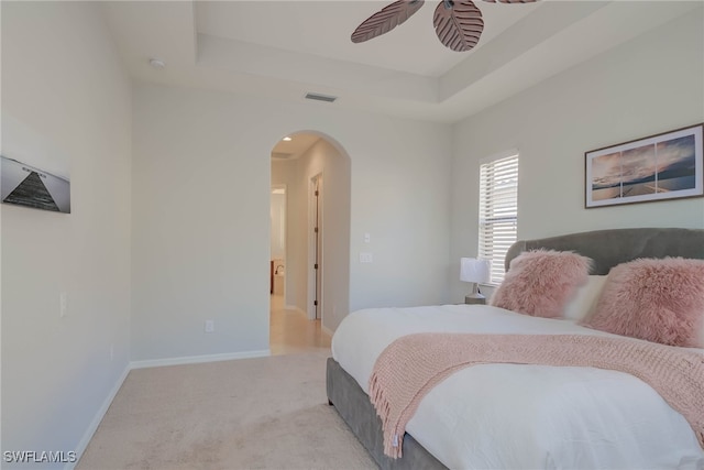 8336 Adelio Ln, Fort Myers, FL 33912 - bedroom featuring arched walkways, light carpet, a tray ceiling, baseboards, and ceiling fan