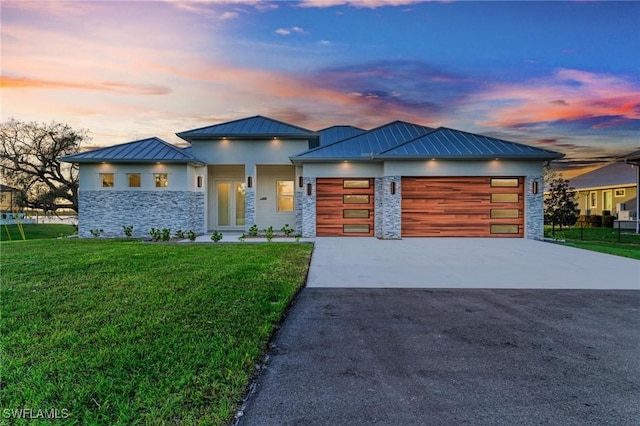 6100 Riverside Dr, Punta Gorda, FL 33982 - view of front of home featuring a standing seam roof, stone siding, a lawn, and an attached garage