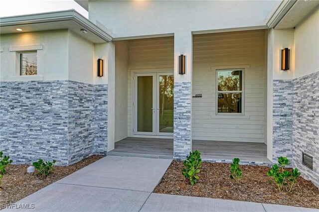 6100 Riverside Dr, Punta Gorda, FL 33982 - view of exterior entry featuring stone siding, stucco siding, and french doors