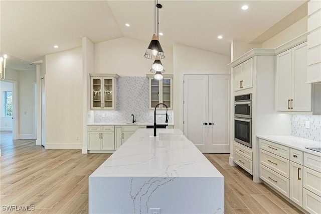 6100 Riverside Dr, Punta Gorda, FL 33982 - kitchen featuring double oven, a sink, a center island with sink, decorative backsplash, and glass insert cabinets