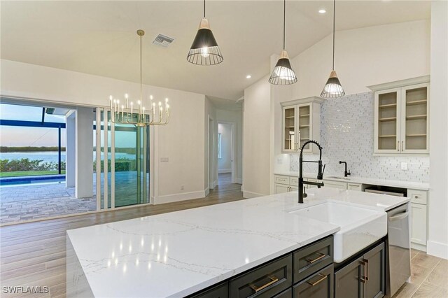 6100 Riverside Dr, Punta Gorda, FL 33982 - kitchen with stainless steel dishwasher, a center island with sink, light wood-style flooring, lofted ceiling, and a sink