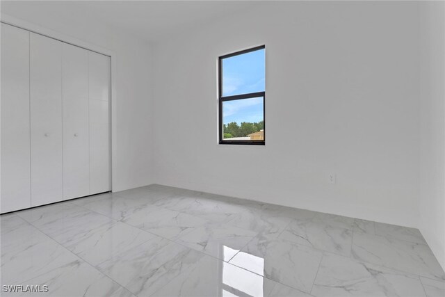 2712 58th St W, Lehigh Acres, FL 33971 - unfurnished bedroom featuring light marble finish flooring and a closet