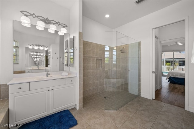 ensuite bathroom featuring tiled shower, ceiling fan, vanity, tile patterned flooring, and recessed lighting