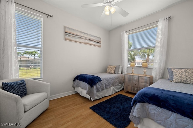 bedroom with light wood finished floors, baseboards, and a ceiling fan