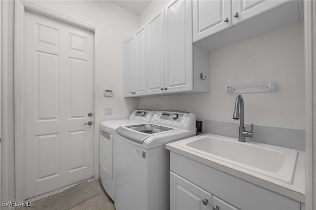 washroom with cabinet space, washing machine and dryer, and light tile patterned floors