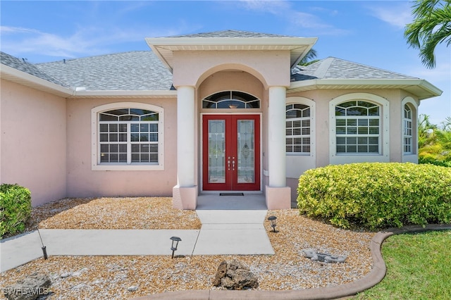 doorway to property featuring roof with shingles and stucco siding
