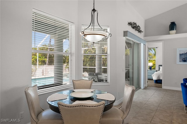 tiled dining space featuring healthy amount of natural light, baseboards, and high vaulted ceiling