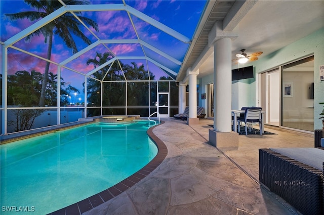 view of swimming pool with a patio area, ceiling fan, a pool with connected hot tub, and glass enclosure