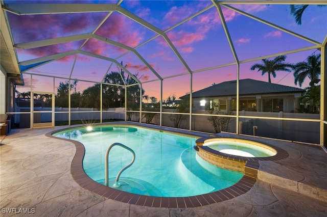 pool at dusk with a patio area, a pool with connected hot tub, and glass enclosure