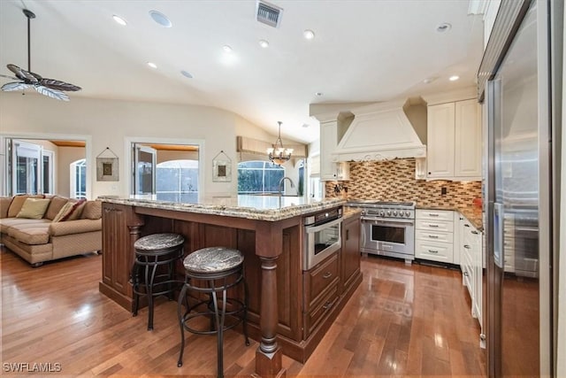 600 Port Side Dr, Naples, FL 34103 - kitchen with high quality appliances, vaulted ceiling, premium range hood, dark wood-style flooring, and a ceiling fan