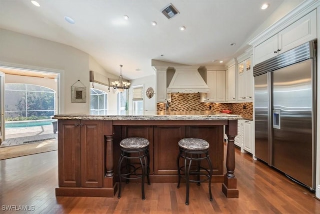 600 Port Side Dr, Naples, FL 34103 - kitchen with stainless steel built in fridge, premium range hood, dark wood-style floors, a chandelier, and tasteful backsplash