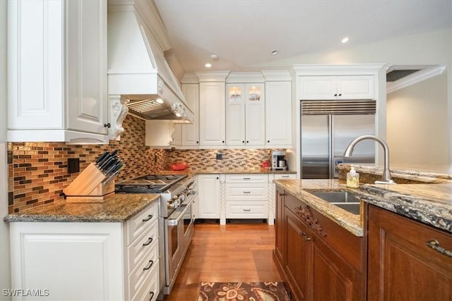 600 Port Side Dr, Naples, FL 34103 - kitchen with high quality appliances, custom range hood, white cabinetry, stone countertops, and backsplash