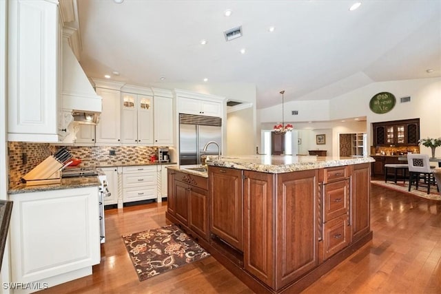 600 Port Side Dr, Naples, FL 34103 - kitchen with premium appliances, lofted ceiling, a large island with sink, tasteful backsplash, and white cabinets