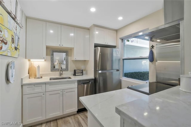 683 12th Ave S Unit 683, Naples, FL 34102 - kitchen with appliances with stainless steel finishes, a sink, wall chimney exhaust hood, light wood-style floors, and white cabinets