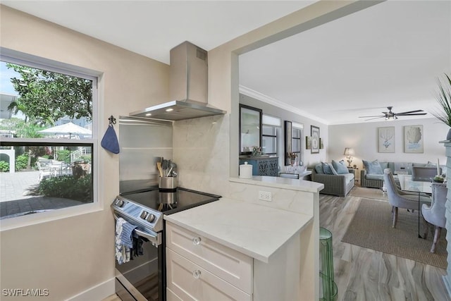 683 12th Ave S Unit 683, Naples, FL 34102 - kitchen featuring wall chimney range hood, stainless steel range with electric stovetop, light countertops, ceiling fan, and white cabinets