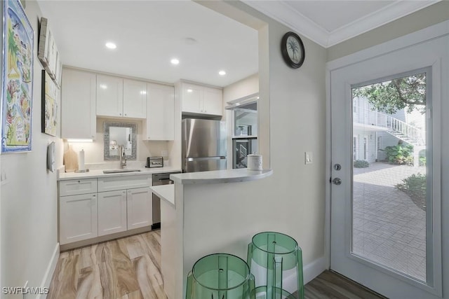 683 12th Ave S Unit 683, Naples, FL 34102 - kitchen with stainless steel appliances, a sink, light countertops, white cabinetry, and ornamental molding
