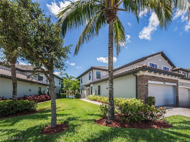 9469 Casoria Ct Unit 101, Naples, FL 34113 - view of side of property with stucco siding, a lawn, stone siding, an attached garage, and a tiled roof