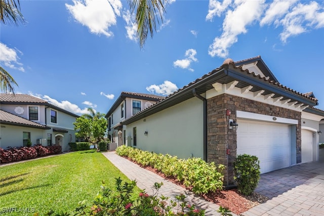9469 Casoria Ct Unit 101, Naples, FL 34113 - view of side of property with stone siding, an attached garage, a yard, stucco siding, and driveway