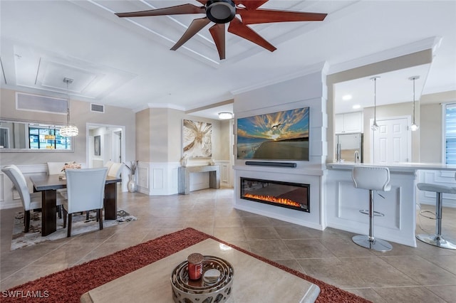9469 Casoria Ct Unit 101, Naples, FL 34113 - tiled living room featuring a decorative wall, a ceiling fan, a fireplace, a wainscoted wall, and a chandelier