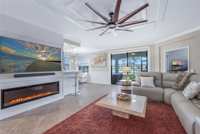 9469 Casoria Ct Unit 101, Naples, FL 34113 - living room featuring a glass covered fireplace, tile patterned floors, a decorative wall, a ceiling fan, and ornamental molding