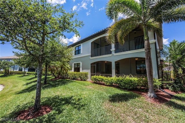 9469 Casoria Ct Unit 101, Naples, FL 34113 - back of house featuring stucco siding, a yard, and a balcony