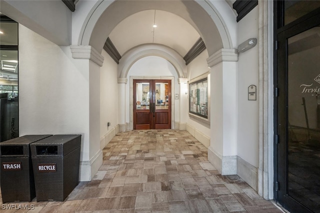 9469 Casoria Ct Unit 101, Naples, FL 34113 - corridor with lofted ceiling, arched walkways, baseboards, stone finish flooring, and french doors