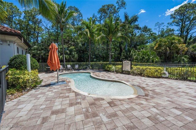 9469 Casoria Ct Unit 101, Naples, FL 34113 - community pool featuring a patio area and view of wooded area