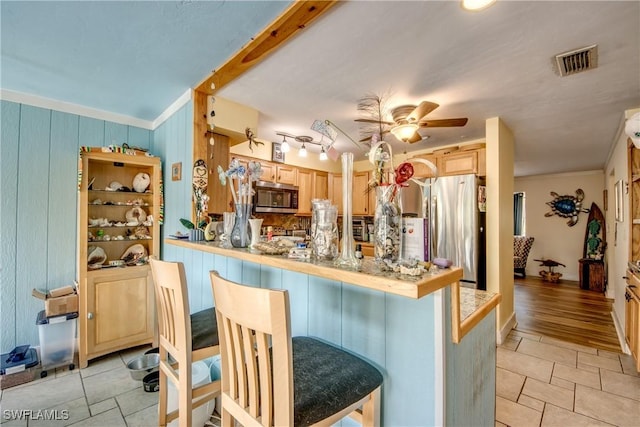 5905 Untermeyer Ct, North Fort Myers, FL 33903 - kitchen with appliances with stainless steel finishes, ornamental molding, light countertops, a peninsula, and a breakfast bar