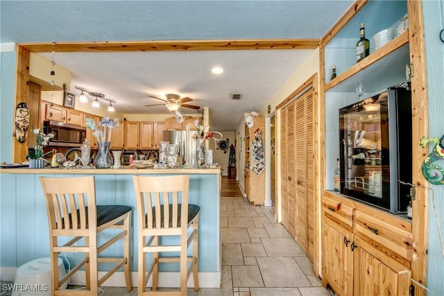 5905 Untermeyer Ct, North Fort Myers, FL 33903 - kitchen featuring appliances with stainless steel finishes, light stone finish floors, light brown cabinetry, a peninsula, and a kitchen breakfast bar