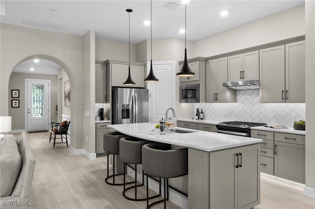 9284 Cormorant Dr, Naples, FL 34120 - kitchen with stainless steel appliances, gray cabinetry, a sink, under cabinet range hood, and recessed lighting