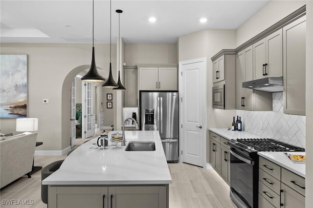 9284 Cormorant Dr, Naples, FL 34120 - kitchen featuring appliances with stainless steel finishes, a sink, gray cabinets, under cabinet range hood, and decorative backsplash