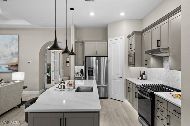 9284 Cormorant Dr, Naples, FL 34120 - kitchen featuring appliances with stainless steel finishes, gray cabinetry, a sink, under cabinet range hood, and tasteful backsplash
