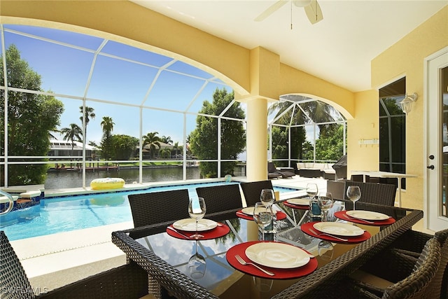 outdoor pool with a water view, ceiling fan, a lanai, and a patio area