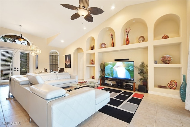 tiled living area featuring built in shelves, vaulted ceiling, ceiling fan, arched walkways, and baseboards