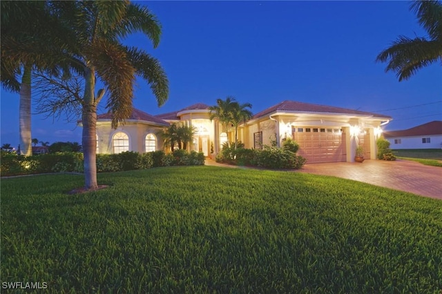 mediterranean / spanish-style house featuring an attached garage, driveway, a yard, and stucco siding