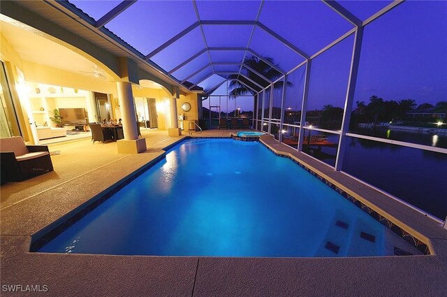 pool at night with a patio, a pool with connected hot tub, a lanai, and a ceiling fan