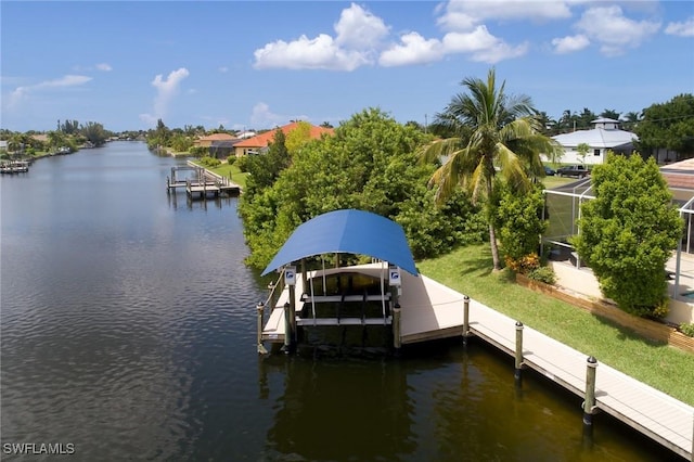 dock area with boat lift, a water view, a lanai, and a yard