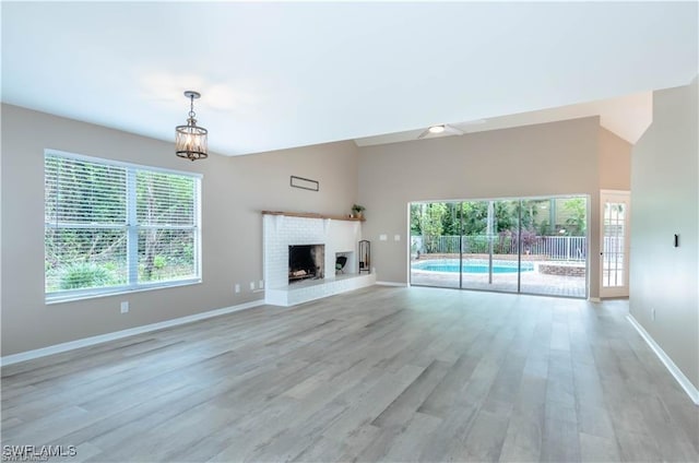 1431 Monarch Cir Unit B8, Naples, FL 34116 - unfurnished living room with healthy amount of natural light, baseboards, light wood-style flooring, and a fireplace with raised hearth