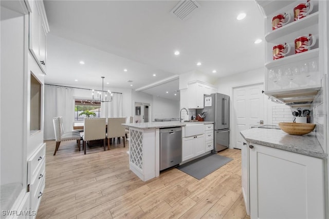 1300 Hilltop Dr, Naples, FL 34103 - kitchen featuring stainless steel appliances, white cabinets, a peninsula, light wood-style floors, and light stone counters