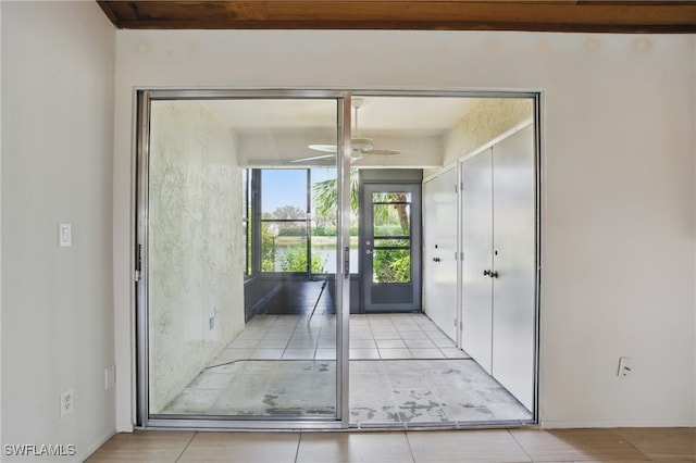 doorway featuring a ceiling fan and tile patterned floors