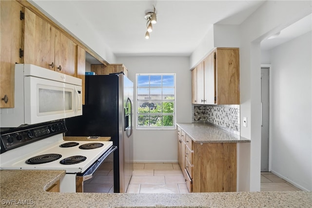 kitchen with white appliances, backsplash, light tile patterned floors, light stone countertops, and baseboards