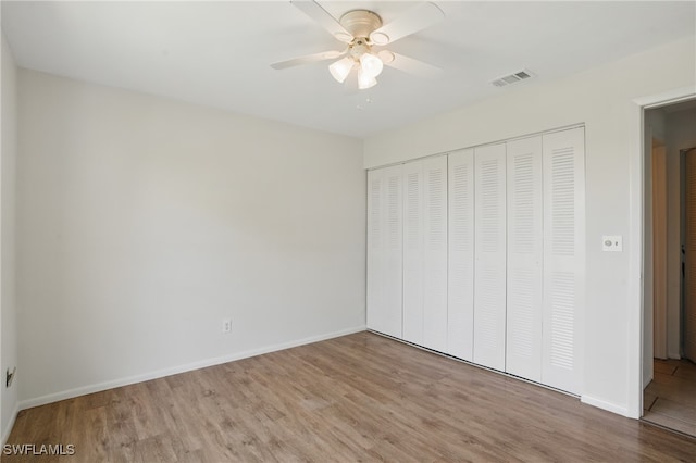 unfurnished bedroom with wood finished floors, a closet, baseboards, and ceiling fan