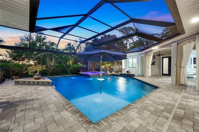 1817 Piccadilly Cir, Cape Coral, FL 33991 - pool at dusk featuring a patio area, a ceiling fan, a pool with connected hot tub, and a lanai