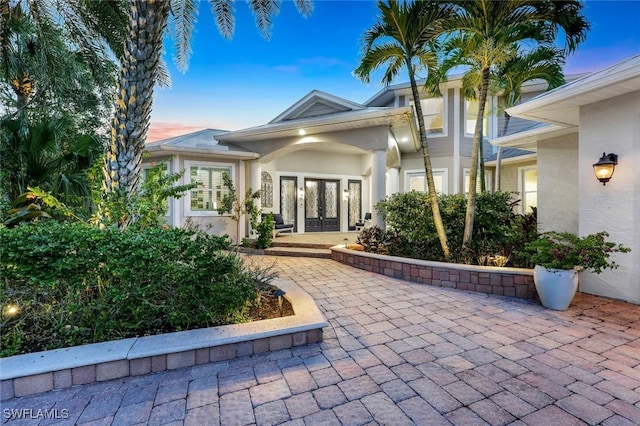 1817 Piccadilly Cir, Cape Coral, FL 33991 - exterior entry at dusk featuring french doors and stucco siding
