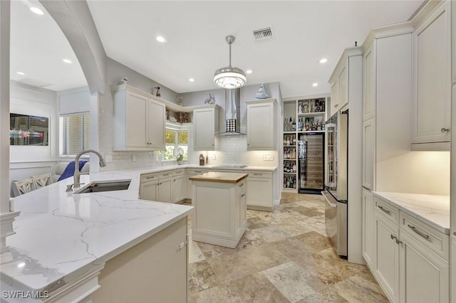 1817 Piccadilly Cir, Cape Coral, FL 33991 - kitchen featuring a sink, wall chimney exhaust hood, high end refrigerator, decorative backsplash, and a peninsula