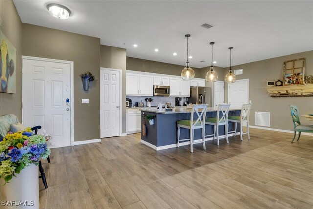 11711 Pasetto Ln Unit 407, Fort Myers, FL 33908 - kitchen with stainless steel appliances, a breakfast bar, white cabinetry, recessed lighting, and light wood-style floors