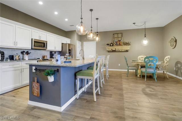 11711 Pasetto Ln Unit 407, Fort Myers, FL 33908 - kitchen with appliances with stainless steel finishes, baseboards, a center island with sink, white cabinetry, and recessed lighting