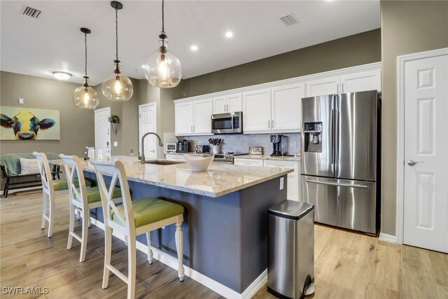 11711 Pasetto Ln Unit 407, Fort Myers, FL 33908 - kitchen featuring appliances with stainless steel finishes, a sink, white cabinetry, a breakfast bar, and light wood-type flooring